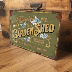 an old fashioned garden shed sign sitting on top of a wooden box with metal handles