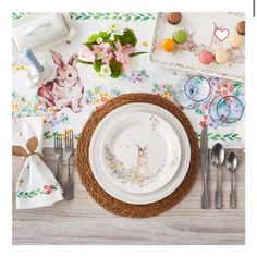 a table set for easter with bunny plates and utensils, napkins and flowers