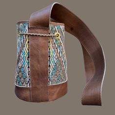 Score some style points with Intertwined's Small Huipil Bucket Bag! This dazzling piece is handcrafted with a vintage huipil (a traditional Mayan blouse) and vegetable-tanned leather. Its interior has a zip pocket and a slot pocket, perfect for stashing your phone, wallet, keys, and whatever else you need to bring along. And it's handmade by Guatemalan artisans at Cuero Malec. It's sure to get stares and questions from your pals - 'cause this bag is an absolute show-stealer! Handwoven Leather Bucket Bag For Everyday, Everyday Handwoven Leather Bucket Bag, Handwoven Brown Leather Bucket Bag, Handwoven Leather Bucket Bag For Daily Use, Brown Leather Handwoven Bucket Bag, Artisan Style Bucket Bag For Festivals, Artisan Bucket Bag For Festival, Artisan Festival Bucket Bag, Artisan Bucket Tote Bag For Festivals