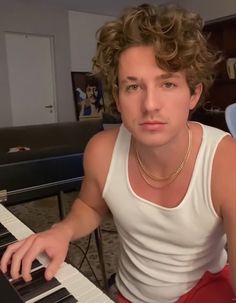 a man with curly hair sitting at a piano