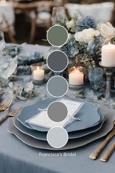 the table is set with blue and gray plates, silverware, candles and flowers