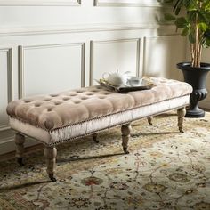 a bench sitting on top of a rug next to a vase and potted plant