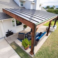 a covered patio with couches and potted plants on the lawn next to it