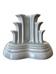 a white ceramic vase with four curved sections