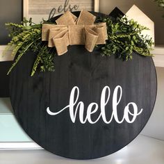 a wooden sign with the word hello painted on it and two bows hanging from it