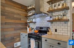 a kitchen with wooden shelves and white tile backsplash, stainless steel stove top oven