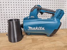 a blue and black tool sitting on top of a wooden table next to a cup