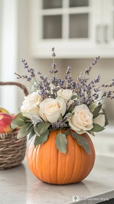 a vase filled with white flowers sitting on top of a table next to an orange pumpkin