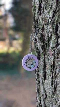 a purple keychain hanging from the side of a tree