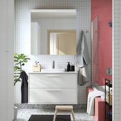 a bathroom with pink and white tiles on the walls, black rugs and a wooden stool