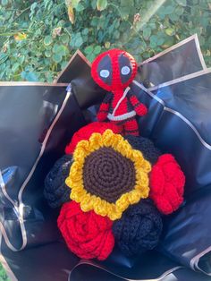 a crocheted deadpool doll sitting on top of a black chair with a sunflower