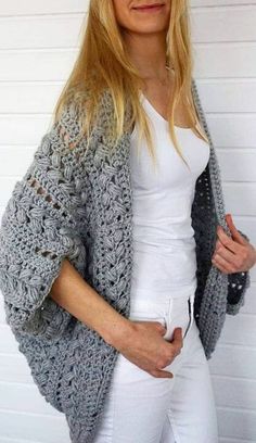 a woman wearing white pants and a gray crochet cardigan