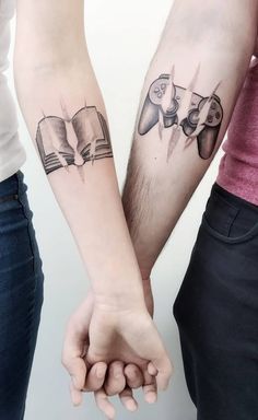 two people are holding hands with tattoos on their arms and one is reading a book