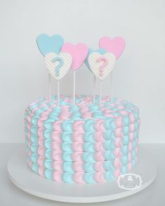 there is a cake with hearts on top and two candles in the shape of question marks