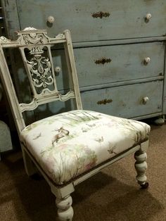 an old chair sitting in front of a dresser with drawers and drawers on it's sides