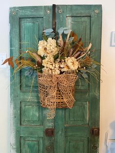 a basket with flowers hanging on a green door