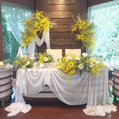 the table is covered with white and yellow flowers, greenery and candles on it