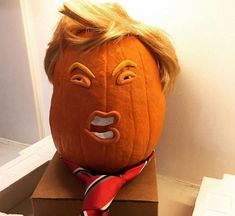 a pumpkin with a tie around it's neck sitting on top of a cardboard box