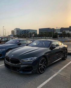 three bmw cars parked in a parking lot with buildings in the backgrouds