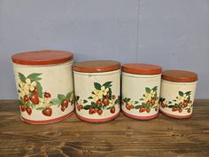 four canisters with flowers and berries painted on them