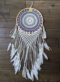 a white and purple dream catcher on a wooden floor