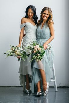 two beautiful women standing next to each other holding bouquets in their hands and posing for the camera