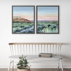 two paintings hanging on the wall above a bench with a plant in front of it