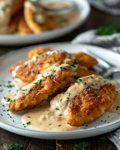 two white plates topped with fried chicken covered in gravy