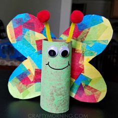 a toilet paper roll with a butterfly on it and some pom poms around the eyes