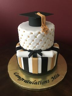 a graduation cake is decorated with black and white stripes, gold accents and a tassel