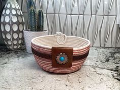 a basket sitting on top of a counter next to two vases and a cactus