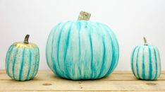 three painted pumpkins sitting on top of a wooden table