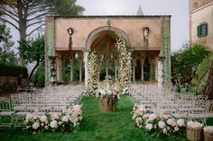 an outdoor ceremony setup with white chairs and flowers