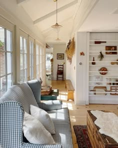 a living room filled with furniture and lots of windows next to a wall covered in bookshelves