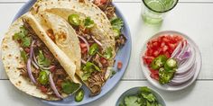 three tacos on a blue plate with onions, peppers and cilantro