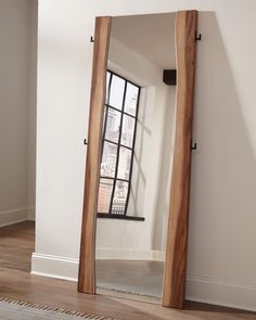 a large mirror sitting on top of a wooden floor next to a white wall in a room