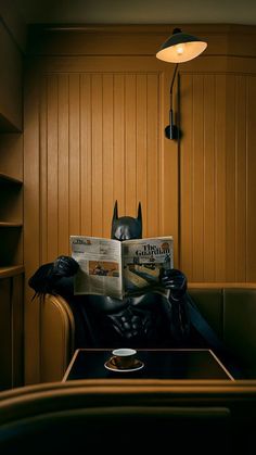 a batman sitting in a chair reading a newspaper