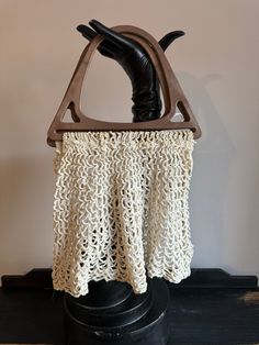 a crocheted purse hanging from a hook on top of a black stand with a leather boot in it