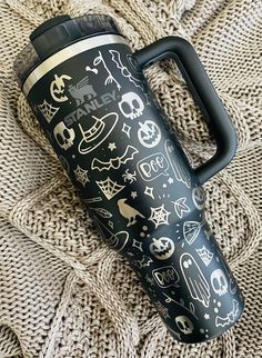 thermos cup is sitting on top of a blanket with skulls and bones all over it