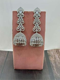 Elevate your style with our Exquisite High-Quality American Diamond Jhumka Earrings, a stunning blend of traditional craftsmanship and contemporary design. These earrings feature meticulously selected American diamonds, each set with precision to radiate brilliance and sophistication. The intricate Jhumka design is a timeless symbol of elegance, perfect for any occasion--be it a grand celebration or a simple evening out. The earrings are crafted from premium materials, ensuring they not only daz Heavy Silver Jhumkas For Reception, Silver Jhumkas With Latkans For Reception, Silver Jhumkas For Reception With Latkans, Silver Jhumkas For Reception, White Jhumkas With Intricate Design For Reception, Bollywood Style Silver Jhumkas For Reception, Intricate Design Jhumkas For Reception, Reception White Jhumkas With Intricate Design, Silver Fusion Jhumkas For Reception