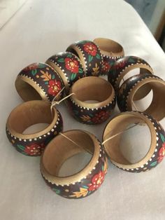 six wooden rings with flowers painted on them sitting on a table top next to each other