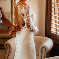 a woman in a wedding dress getting ready to go into her gown for the ceremony