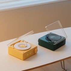 two different colored turntables sitting on top of a table next to each other