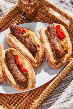 four hot dogs on buns with ketchup and relish sitting on a wicker tray