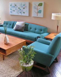 a living room filled with blue couches and wooden tables in front of two paintings on the wall