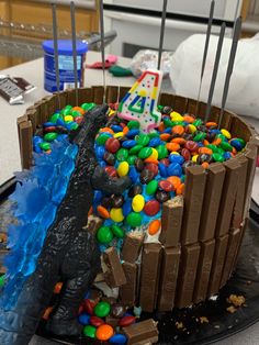 a birthday cake decorated with chocolate, candy and gummy balls is displayed on a table