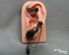 Wire wrapped gothic ear wrap with black onyx stones and chain, no piercing required. It's made of bronze artistic wire, antiqued brass chain, seed beads, an antiqued brass bezel, black onyx beads and cabochon, and a matching black glass briolette bead. One of a kind. For the left ear. You can find more ear wraps here: https://www.etsy.com/shop/bodaszilvia?section_id=10953132&ref=shopsection_leftnav_4 Plz, read my policies before buying. Thank you! If you are interested in news, work in progress Ear Wraps, Felt Pouch, Artistic Wire, Wrap Earrings, Black Onyx Stone, Onyx Bead, Jewelry For Her, Onyx Stone, Gothic Jewelry