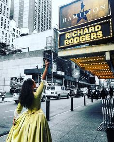 a woman in a yellow dress is waving to the crowd at an outdoor movie theater