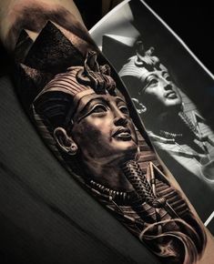 a man's arm with an egyptian tattoo on it, and a photo behind him