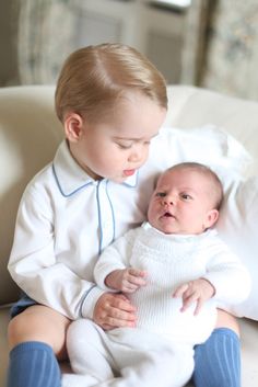 two babies are sitting on a couch together